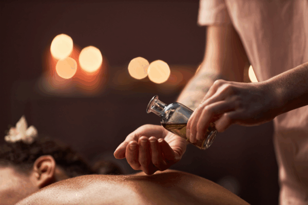 A professional thai massage therapist applying oil on client